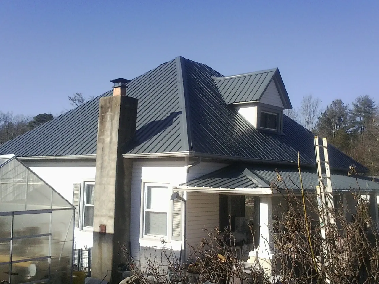 Dark blue standing seam metal roof on a white farmhouse with dormer — Slate & Tile Roof Repair by Roofing Brothers in East Berlin
