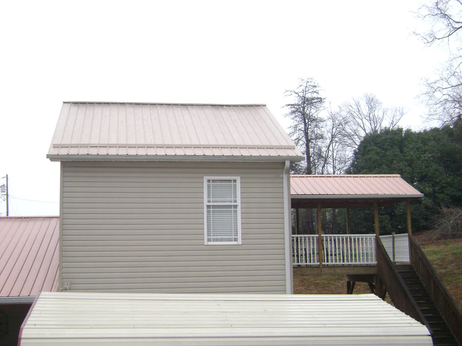Tan metal roofs on a two story addition and attached porch, from a Roof Replacement job in East Berlin